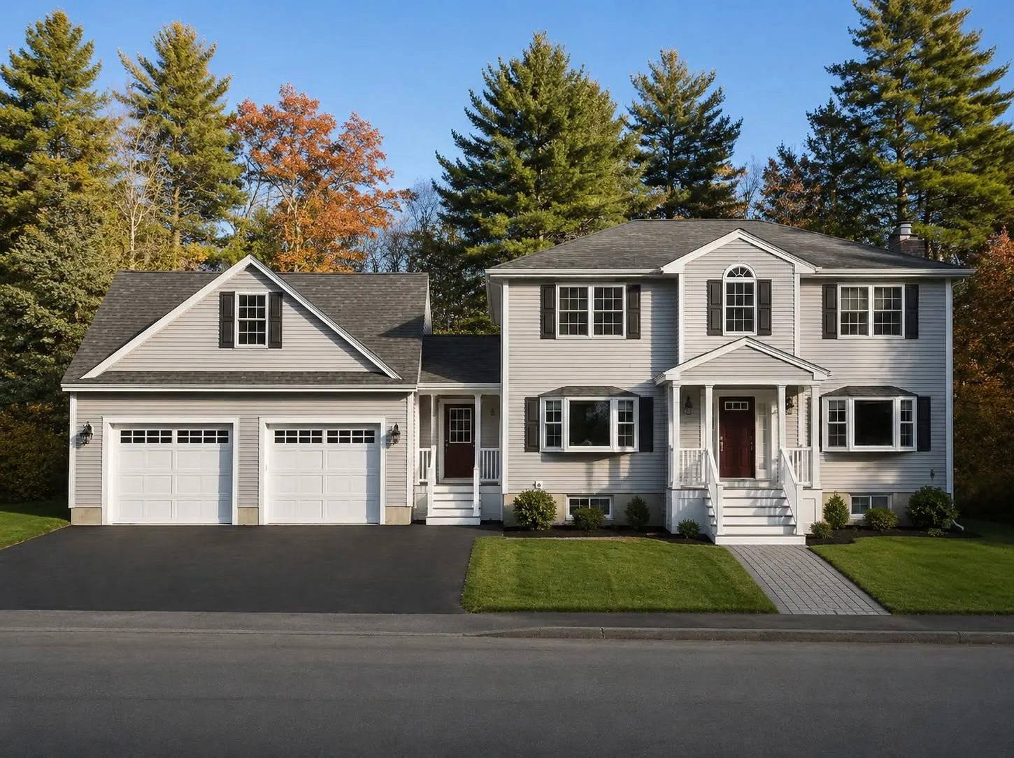 Cream two-story home with black shutters and an attached two-car garage wing with a dormer and a half-round window, in autumn