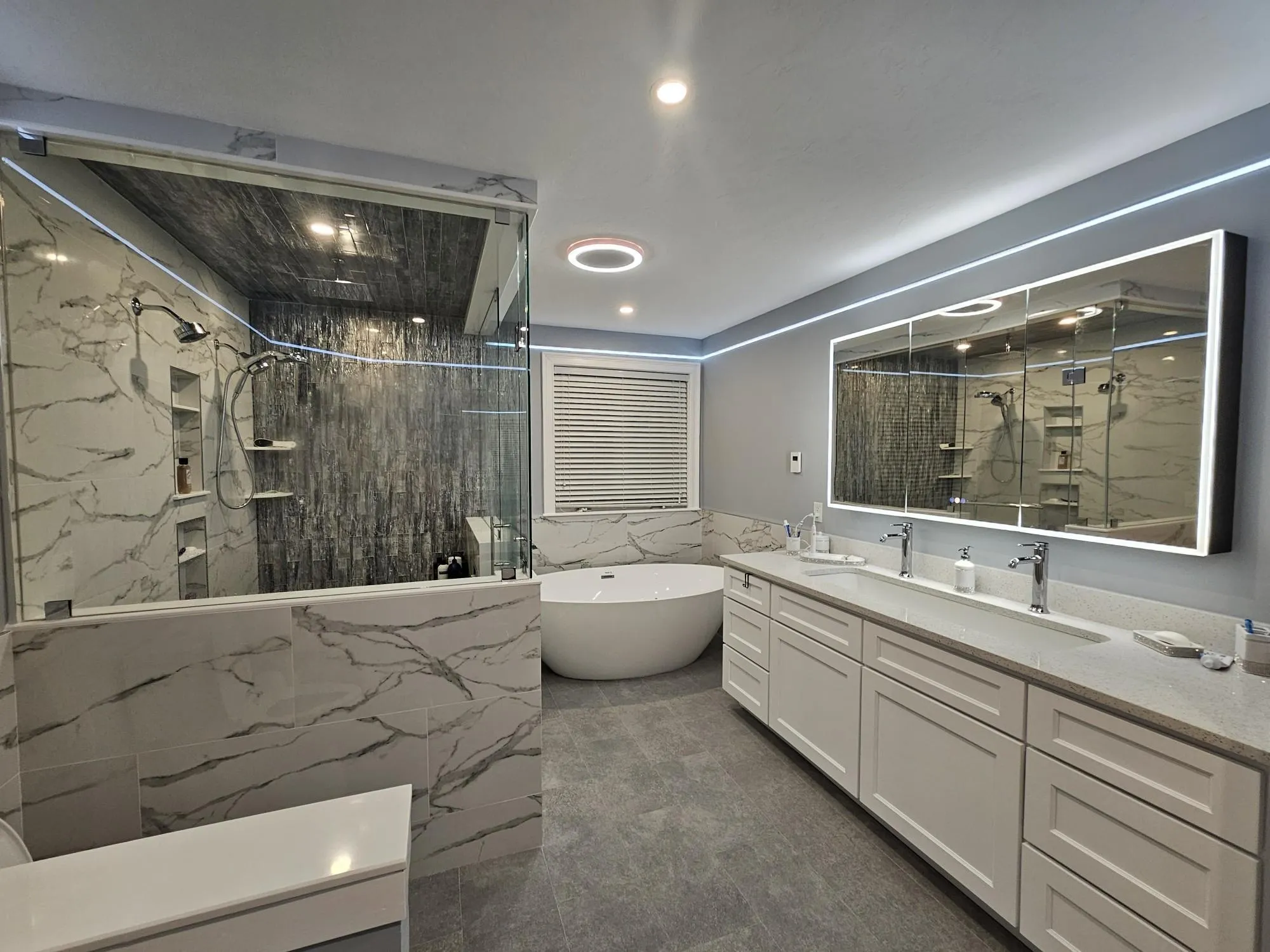 Spa-style bathroom remodel in North Reading, MA with freestanding tub, marble-look surfaces, and lighted mirror