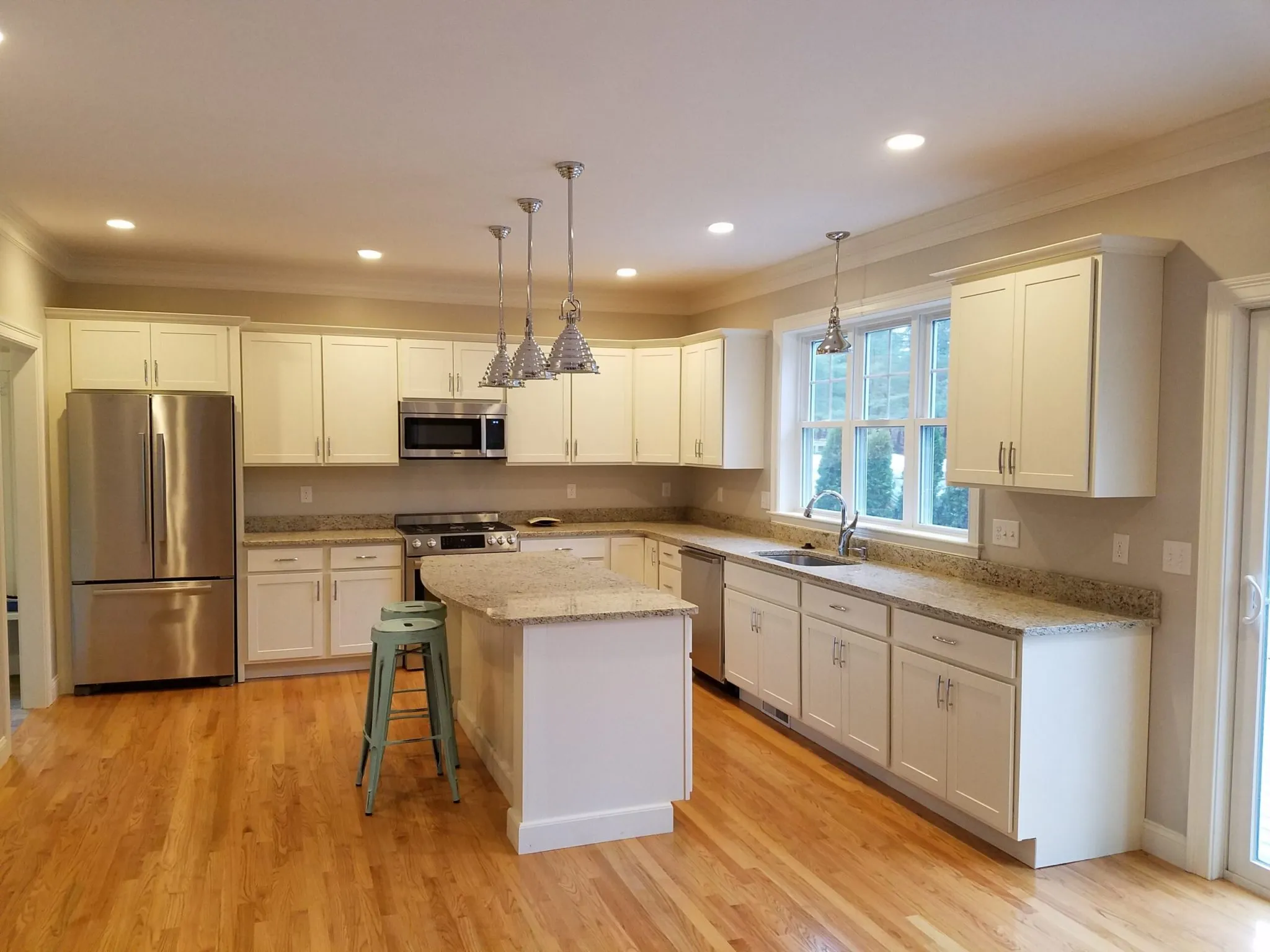 L-shaped kitchen renovation with white cabinets and a new center island in an older New England home, the kind of work CJM Builders does for Reading, MA homeowners