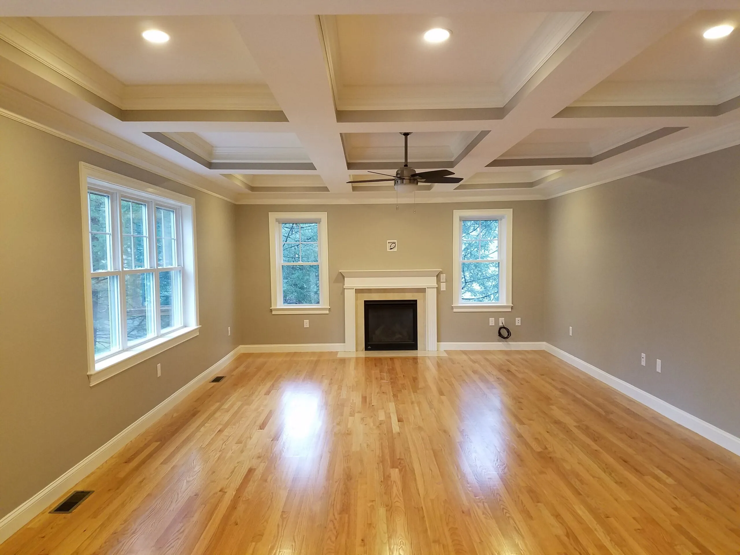 Living room with a coffered ceiling, gas fireplace, and oak hardwood floors
