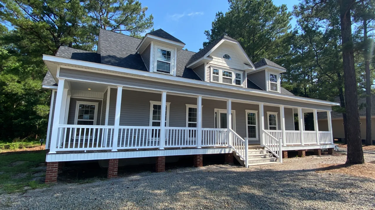 White New England farmhouse with a full-width front porch and gabled dormers