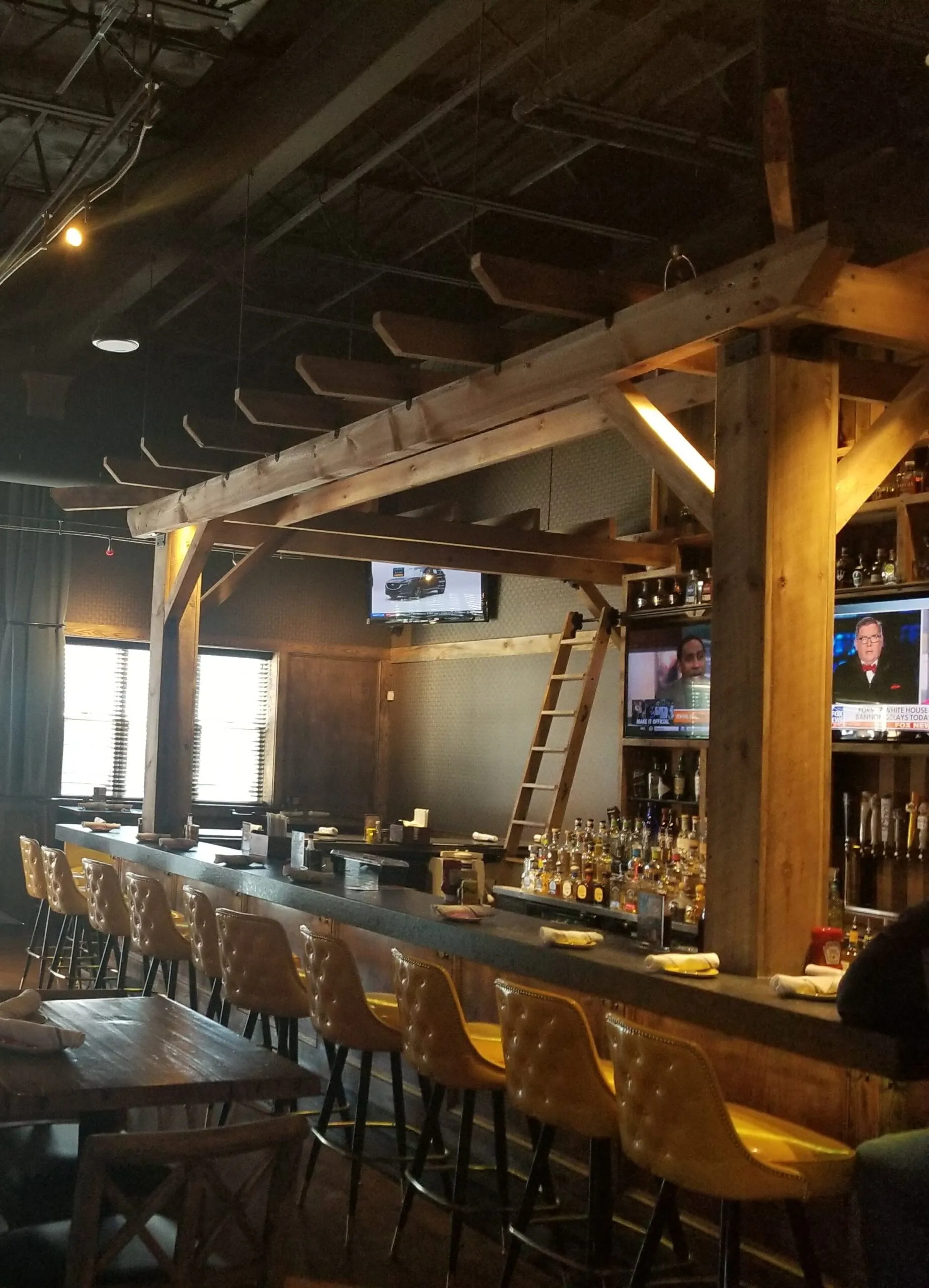 Restaurant interior with a custom wood bar, exposed beams, and pendant lighting