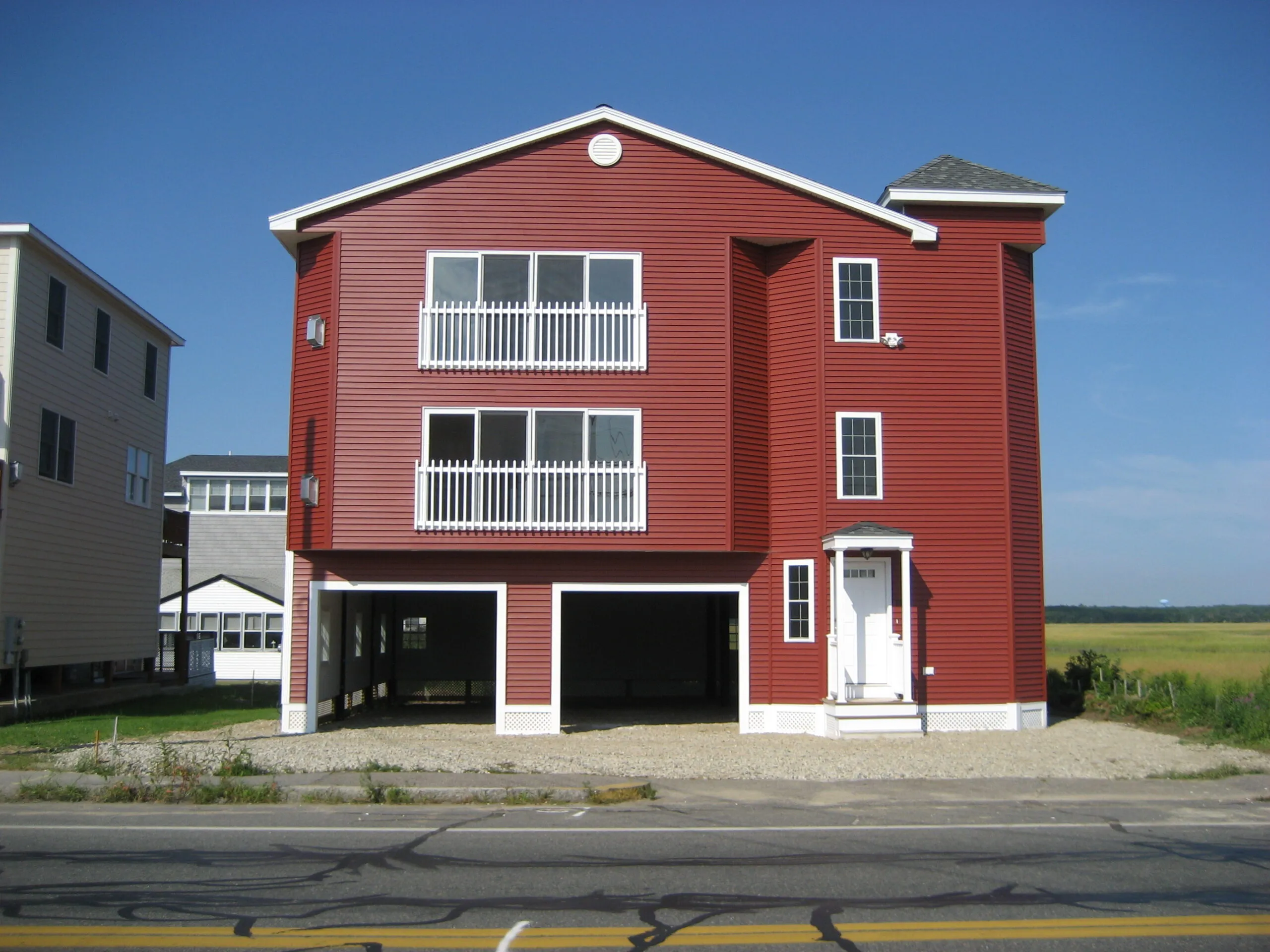 Three-story red building with white-trimmed windows and a two-bay garage