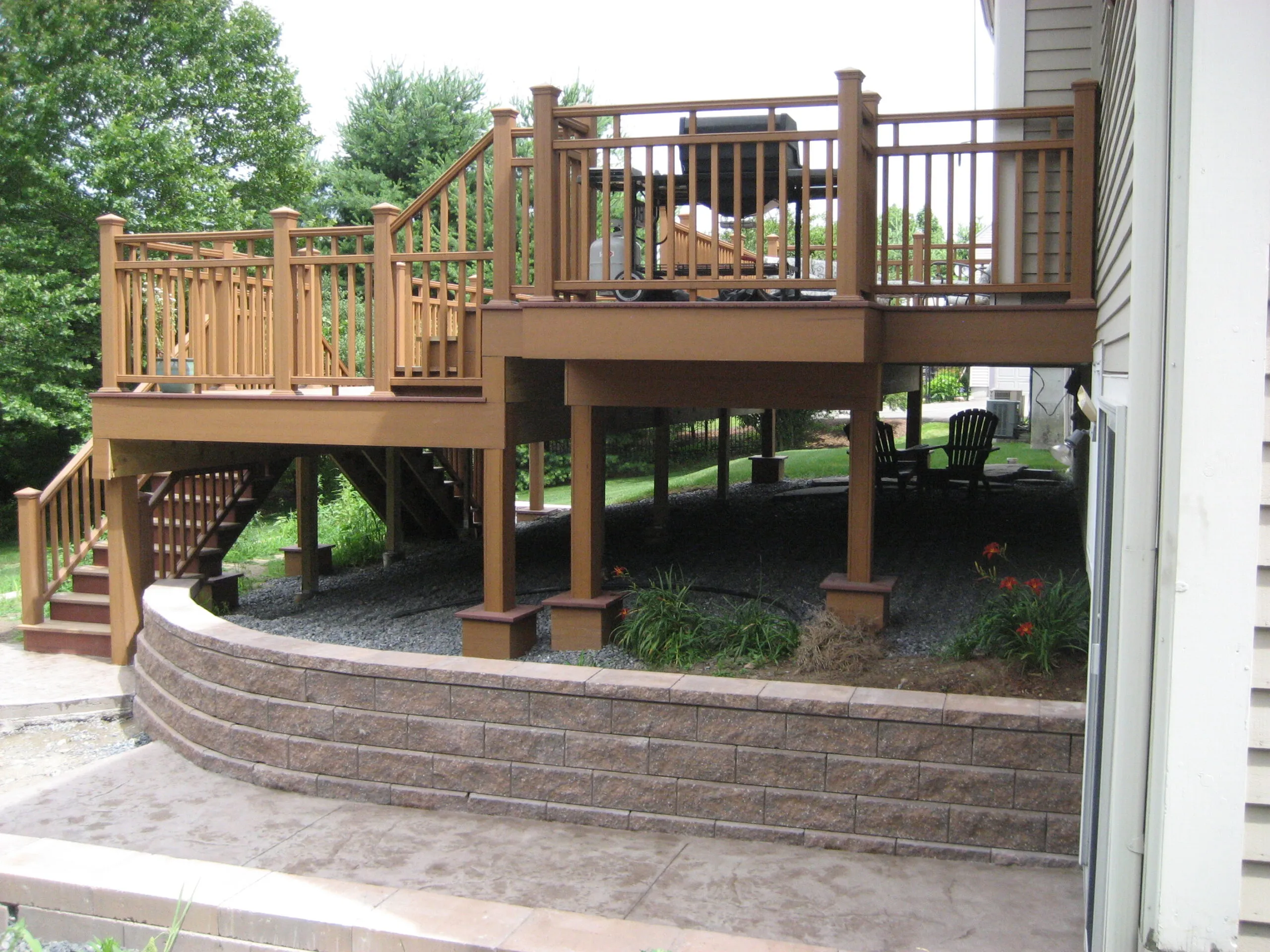 Multi-level cedar deck and stone paver patio built off the back of a home