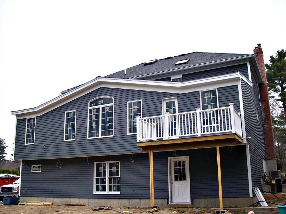 New clapboard siding, white exterior trim, and freshly installed windows on a home under construction by CJM Builders