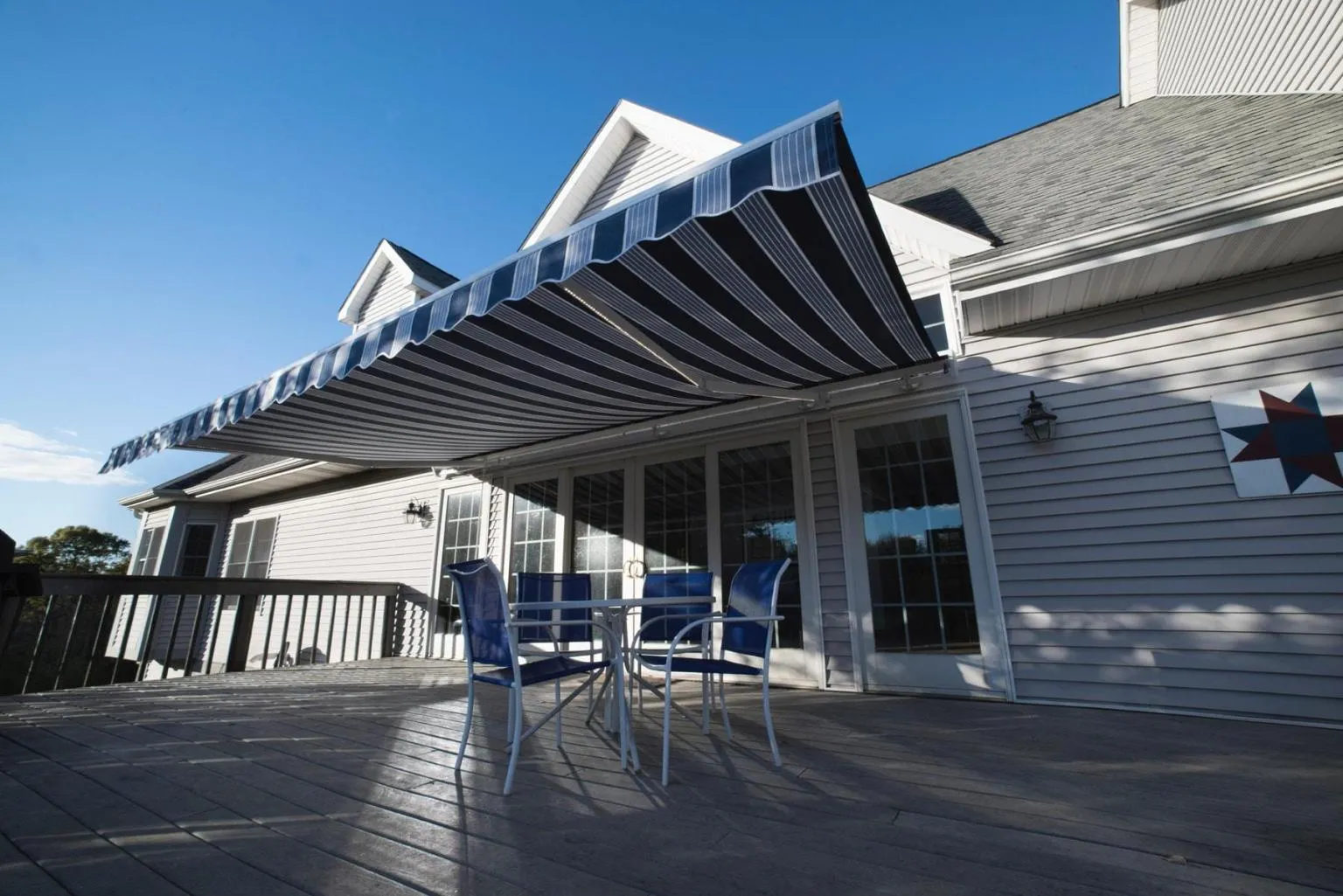 Low-maintenance composite backyard deck with patio seating and French doors at a Massachusetts home by CJM Builders