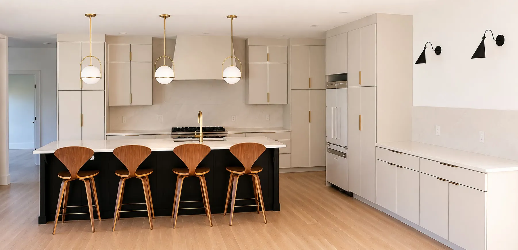 Modern kitchen with flat-panel white cabinets and brass pulls, a black island with four walnut stools, brass globe pendants, black sconces, and light hardwood floors