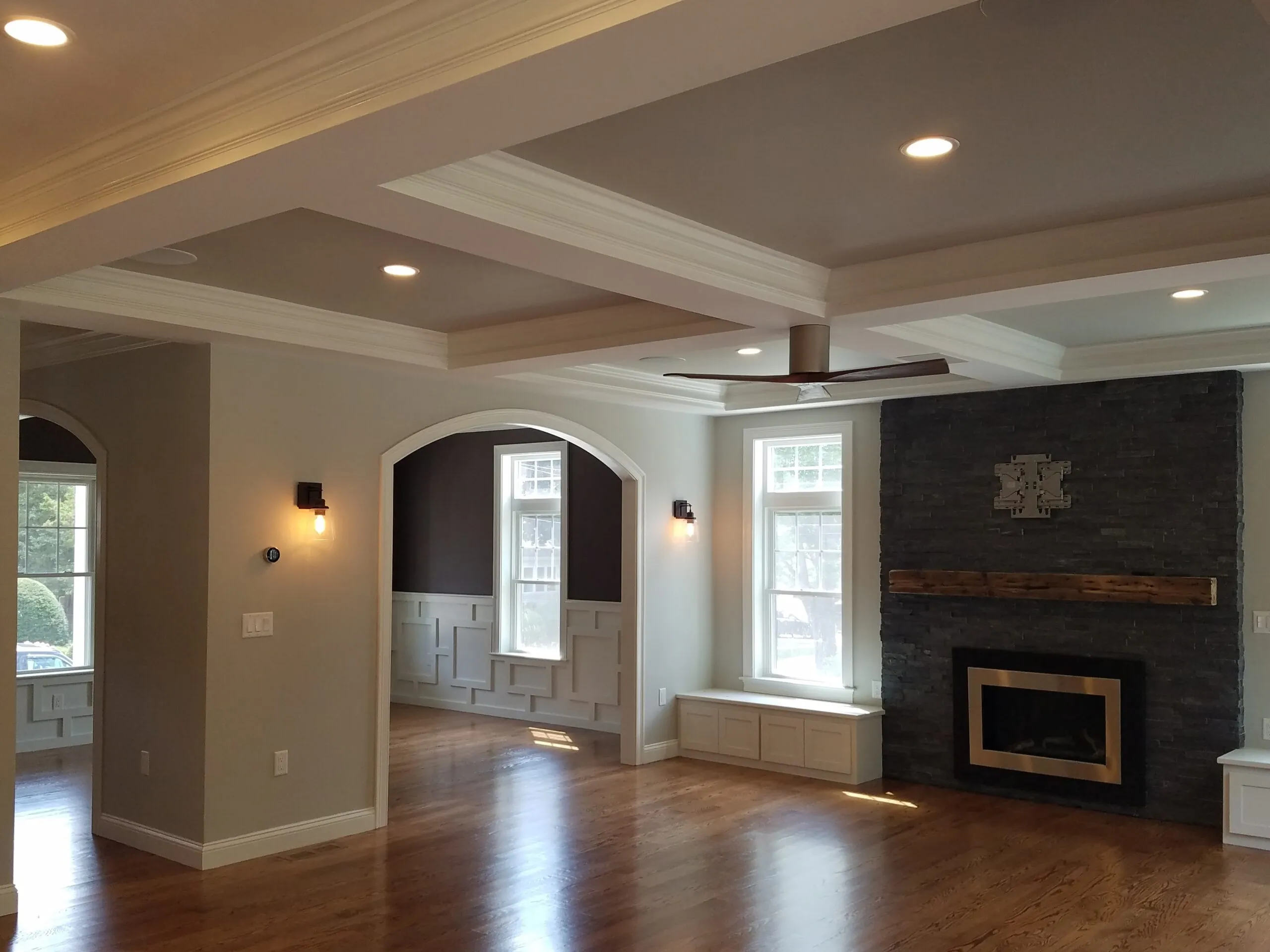 Great room with a coffered ceiling, floor-to-ceiling stone fireplace, and hardwood floors